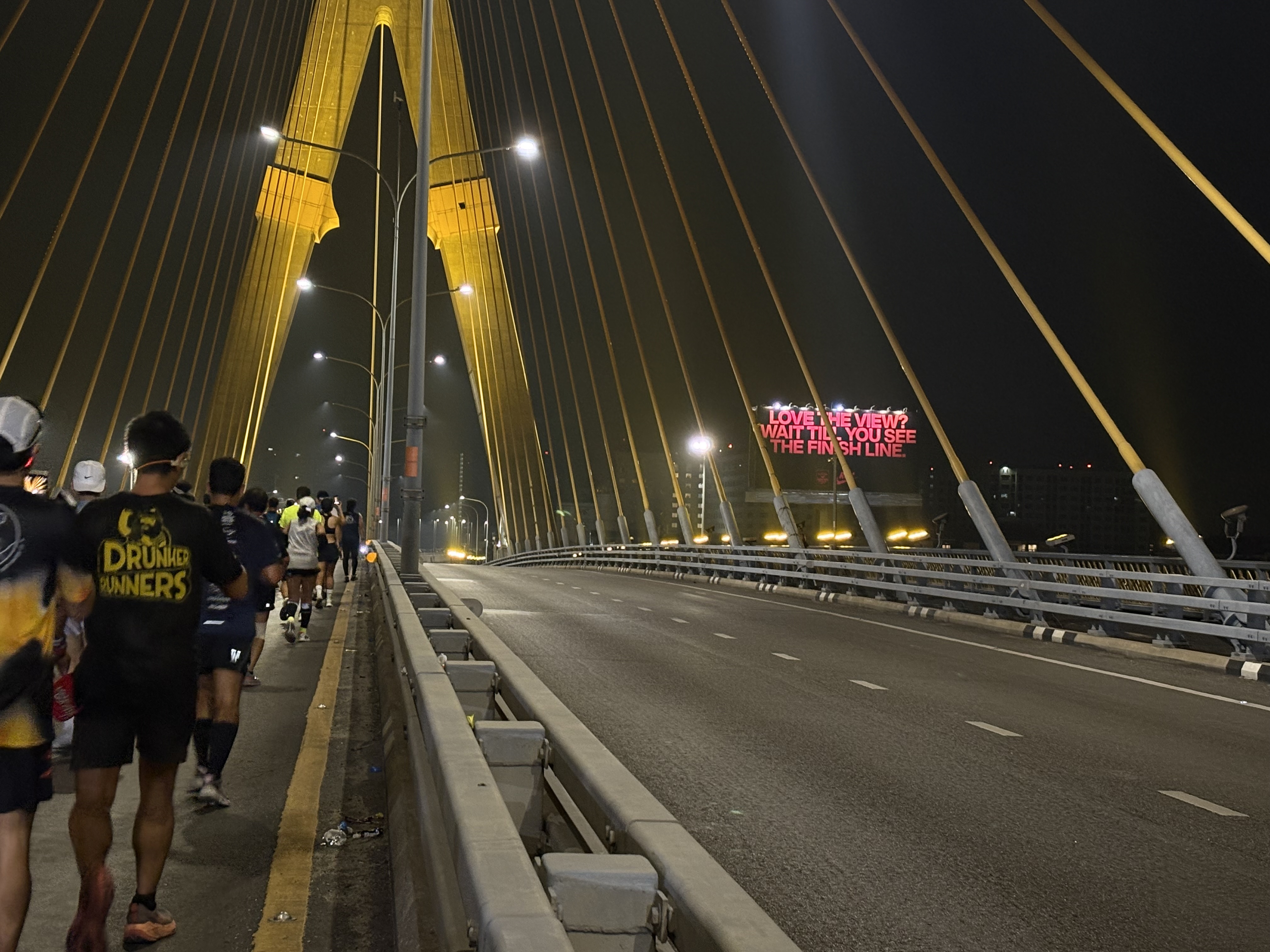 Runners passing a major bridge during a Thailand marathon event